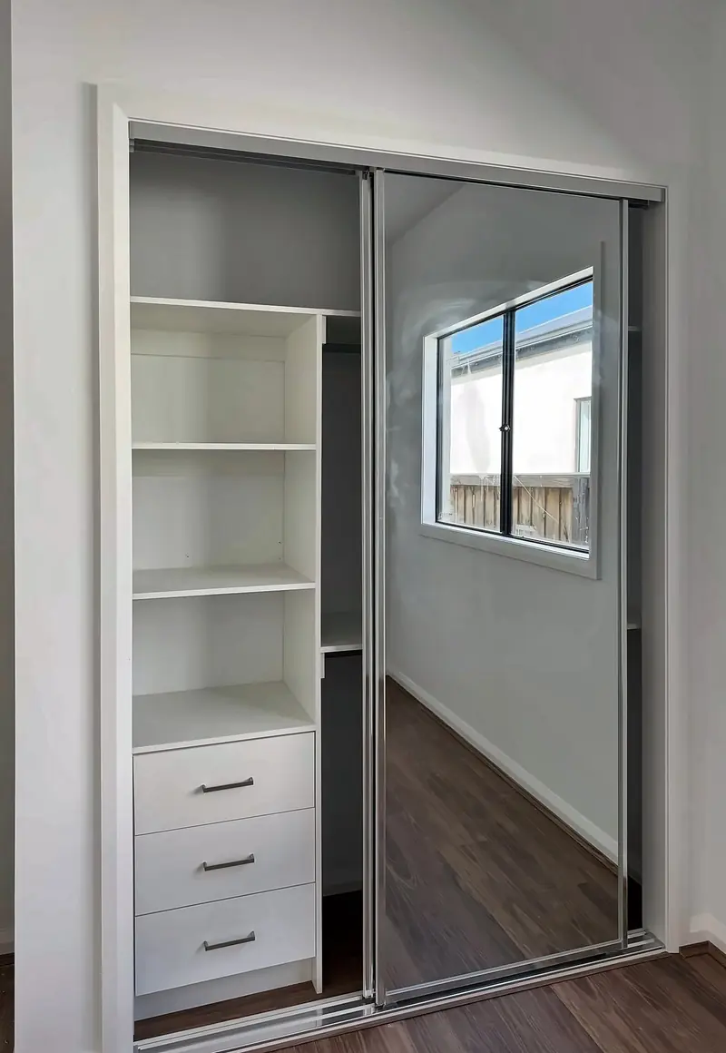Built-in robe with mirrored sliding doors, white shelving and drawers, by Maya Cabinets in Melbourne